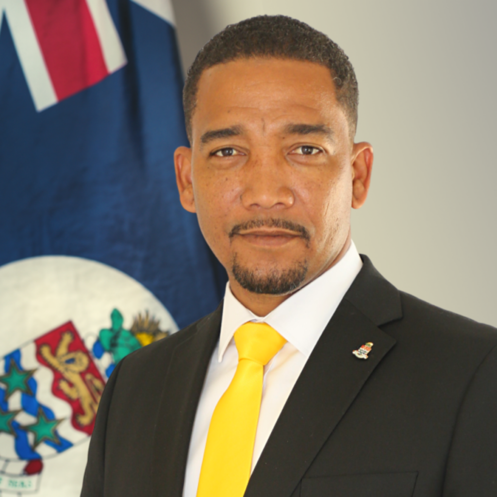 Honourable Kenneth Bryan posing in front of the flag of the Cayman Islands.